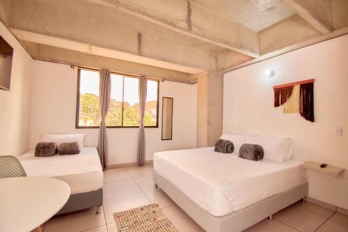 1 dormitorio con 2 camas, mesa y ventanas en MANGATA LIVING, en Medellín