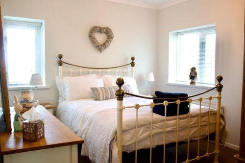 1 dormitorio con 1 cama y un signo cardiaco en la pared en Cartref, 1860s family home. en Bridgend