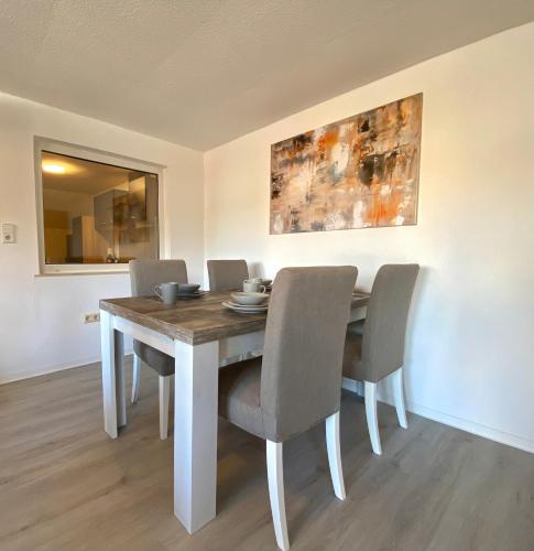 a dining room table with chairs and a painting on the wall at Gemütliche Unterkünfte für längeren Aufenthalt und Monteure inkl Balkon, Waschmaschine, WiFi, Küche und Parkplatz in Aschersleben