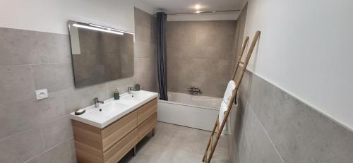 een badkamer met een wastafel, een spiegel en een bad bij Jolie demeure à proximité de La Rochelle in La Jarrie