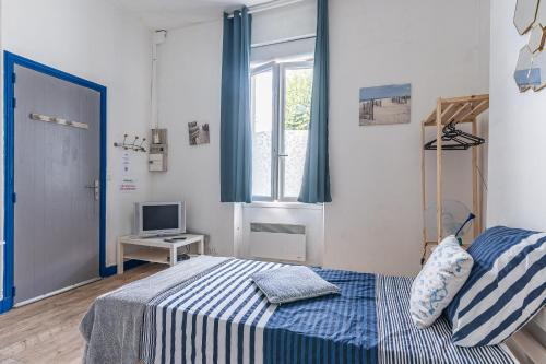 een kleine slaapkamer met een bed en een televisie bij Bureau Lesparre-médoc, le Port in Lesparre-Médoc