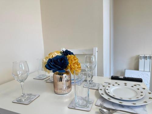 a table with plates and glasses and a vase with flowers at Comfy City Stay in Colchester