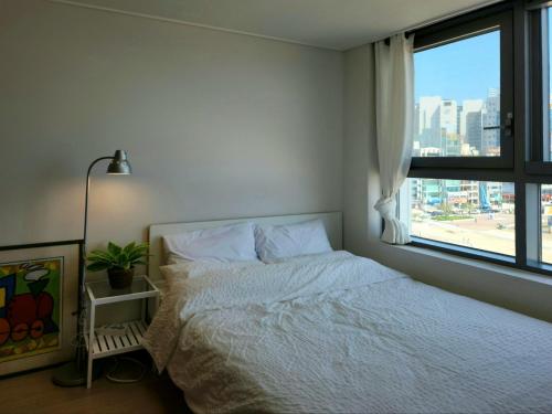 a bedroom with a white bed and a window at Hot place in Busan