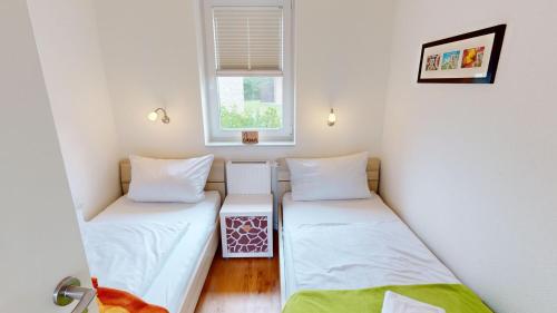 2 łóżka pojedyncze w niewielkim pokoju z oknem w obiekcie Feriendorf Südstrand Haus 35 w mieście Pelzerhaken