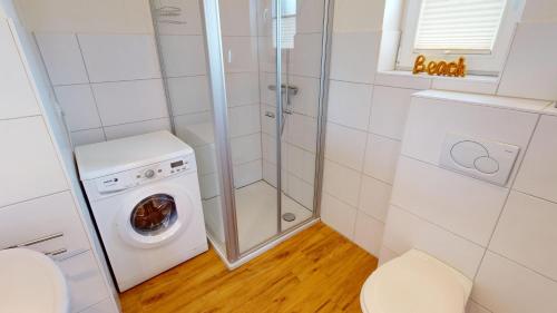 łazienka z pralką i prysznicem w obiekcie Feriendorf Südstrand Haus 35 w mieście Pelzerhaken