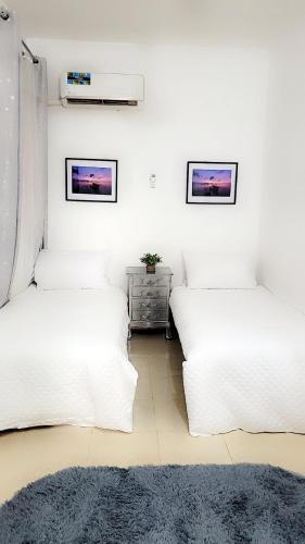 two beds in a room with white walls at Mlandege Town house in Ngambo
