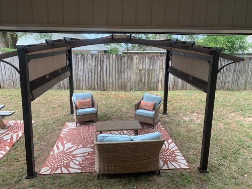 a pergola with two chairs and a table in a yard at D's Florida-Alabama Vacation Home Sleeps 14 Guests in Pensacola