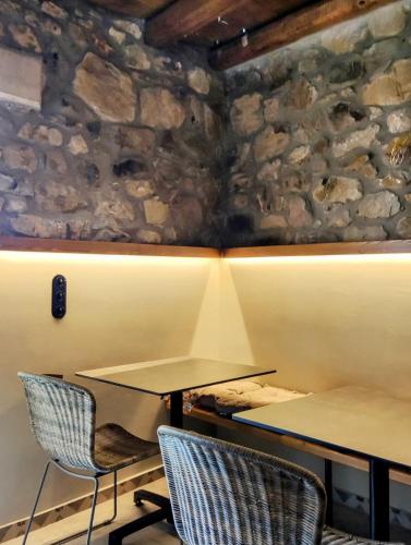 two tables and chairs in a room with a stone wall at Pyrgi Cretan Living & Spa in Pírgos