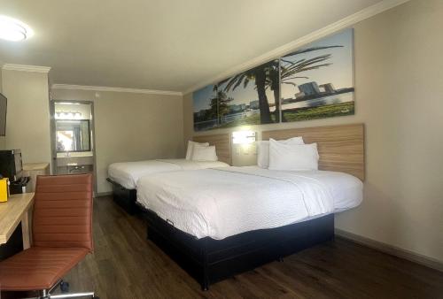 a hotel room with two beds with white sheets at Days Inn by Wyndham Slidell in Slidell