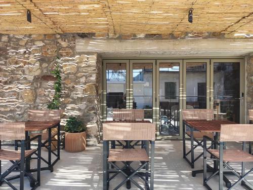 a patio with tables and chairs and a stone wall at Pyrgi Cretan Living & Spa in Pírgos