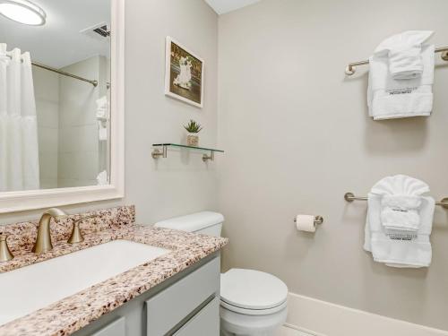 a white bathroom with a toilet and a sink at The Haywood in Savannah