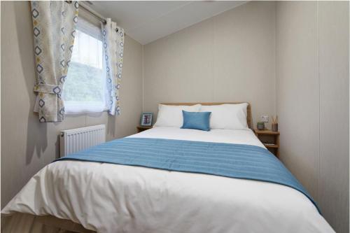 a bedroom with a bed with a blue and white blanket at Caravan on Fantastic site in Dunbar