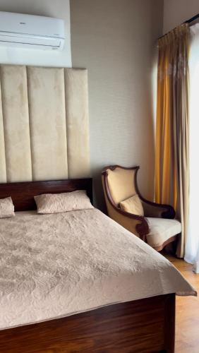 a bedroom with a bed and a chair next to a window at PINETOP RESORT in Khanpur