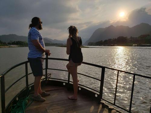 two people standing on a boat on the water at Phong Nha Escape Bungalow in Phong Nha