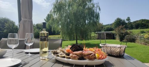 - une table avec une assiette de nourriture et une bouteille de vin dans l'établissement La Prairie Vagabonde, à Surville