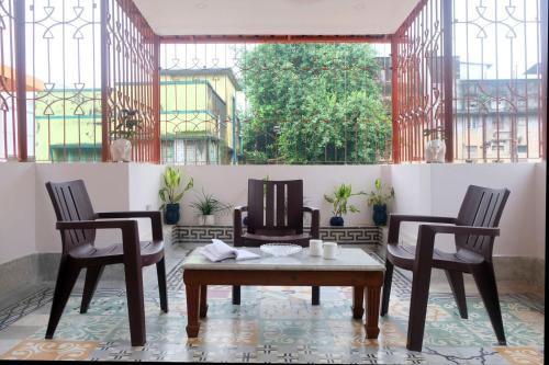 um quarto com duas cadeiras, uma mesa e uma janela em Olys Apartment Gariahat em Calcutá