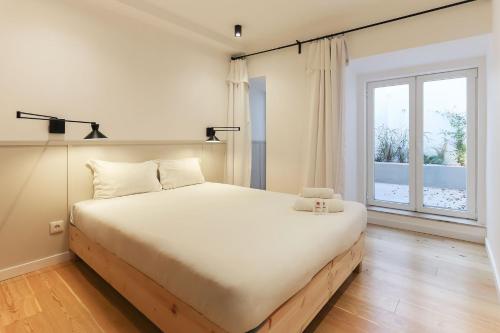 a bedroom with a large bed and a large window at Sao Bento Classic by Homing in Lisbon