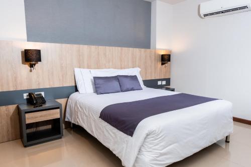 a bedroom with a large bed and a night stand at Hotel Plaza del Lili in Cali