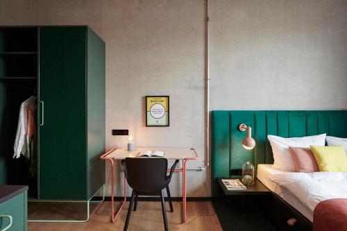 a bedroom with a bed and a desk with a chair at Basecamp Hotel Dortmund in Dortmund