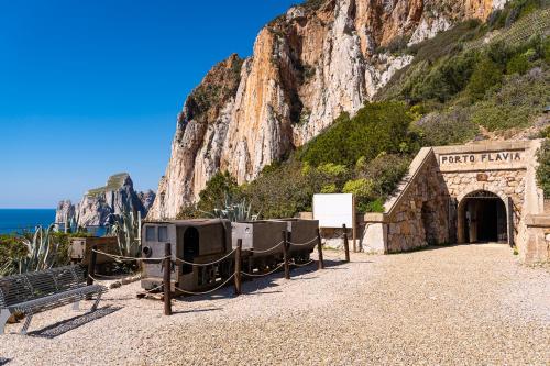 un arco in pietra con una panca di fronte a una montagna di Il Giardino di Giò a Iglesias