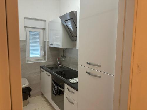 Una pequeña cocina blanca con fregadero y estufa. en Casa Blanca, Biograd na Moru, en Biograd na Moru