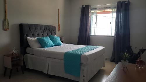 a bedroom with a bed with blue pillows and a window at Encanto do Mar in Praia de Araçatiba