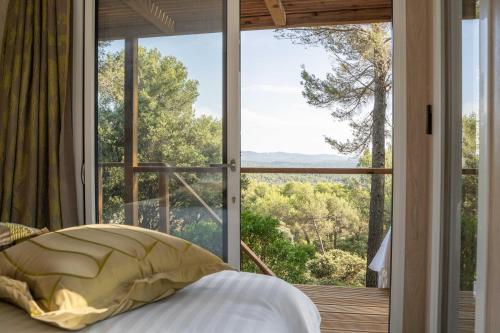 Un dormitorio con una cama y una ventana grande. en Le Chant des Pins Lodge & Spa Massif de l'Etoile, en Saint-Marc-Jaumegarde