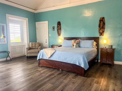 a bedroom with a bed with blue walls and a chair at Victoria House in Frederiksted