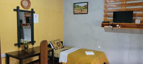 a room with a table and a chair and a tv at SHADOW MASK BUNGALOW in Pattipola