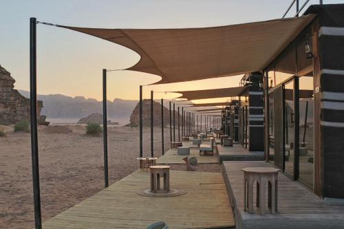 une rangée de tables et de bancs sous des auvents dans le désert dans l'établissement Imagination Luxury Camp, à Disah