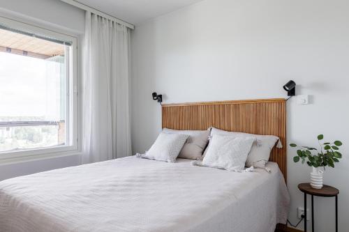 1 dormitorio con 1 cama con sábanas blancas y ventana en Tower Cabin, en Tampere