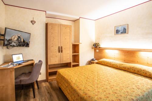 a bedroom with a bed and a desk and a computer at Hotel Bijou in Valtournenche