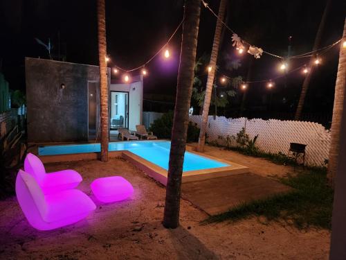 una piscina con sillas de color rosa neón frente a una casa en Quiet and peaceful house, all installations are private, with pool and very close to the beach, en Telchac Puerto