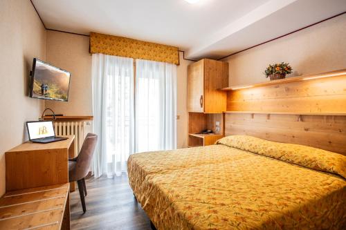 a bedroom with a bed and a desk with a laptop at Hotel Bijou in Valtournenche