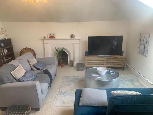 a living room with couches and a flat screen tv at Top Floor. Top Notch. Tranquil Treat. Stone's throw from Thames. in Maidenhead