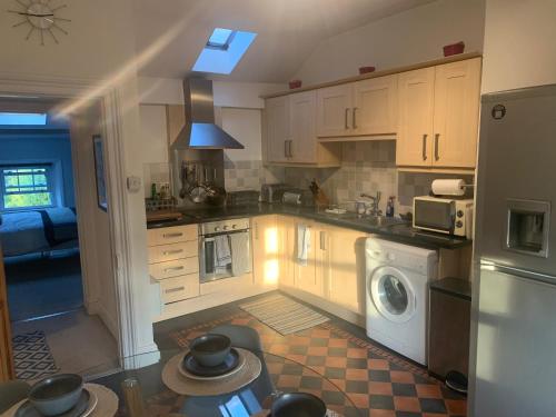 a kitchen with white cabinets and a washer and dryer at Top Floor. Top Notch. Tranquil Treat. Stone's throw from Thames. in Maidenhead