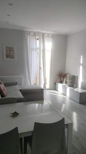Cette chambre blanche comprend un lit, une table et des chaises. dans l'établissement Residenza Il Principe Bilocale Centro, à Parme