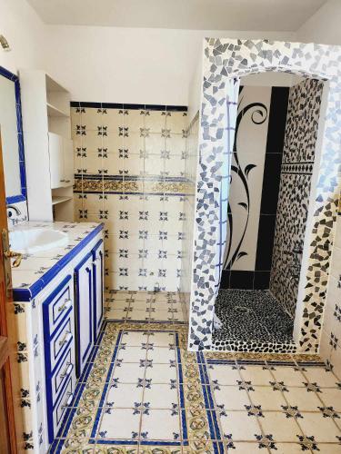 La salle de bains est pourvue d'une douche et de murs carrelés bleus et blancs. dans l'établissement villa en pleine nature, au Muy