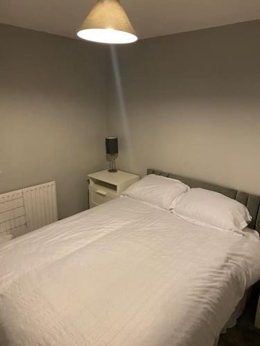 1 dormitorio con 1 cama blanca grande con lámpara en Cosy 1 Bed Home @Stevenage, en Shephall