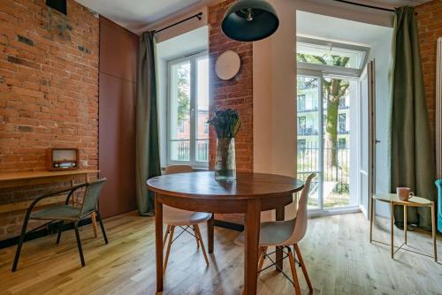 een eetkamer met een tafel en stoelen en een bakstenen muur bij Cozy Studio 5 minut by Warsaw East in Warschau