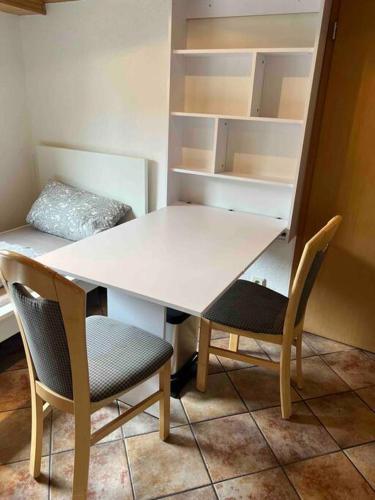 a white table with two chairs and an empty shelf at Gemütliche 1-Zimmer-Wohnung in Pegnitz