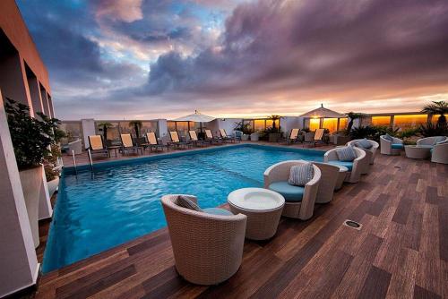 a large swimming pool with chairs and a sunset at Mövenpick Hotel Casablanca in Casablanca