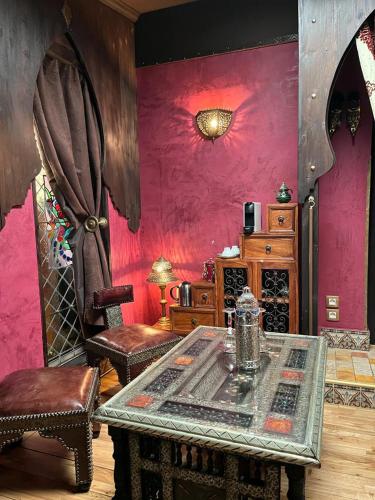 a room with a table and chairs and pink walls at Chambres d'hôtes - Le Nador in Meurchin