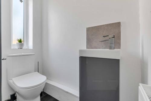 a white bathroom with a toilet and a sink at Silver Stag Properties, 4 BR in Ashby de la Zouch in Smisby