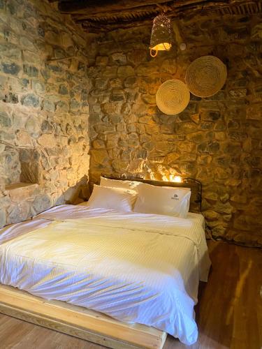 a bedroom with a bed in a stone wall at Hanging Terraces المدرجات المعلقة in Al ‘Aqar