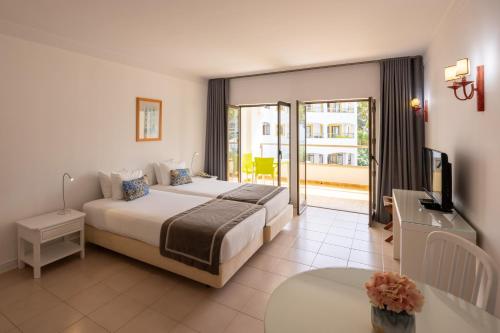 a bedroom with a bed and a television and a balcony at Clube do Lago Hotel in Estoril