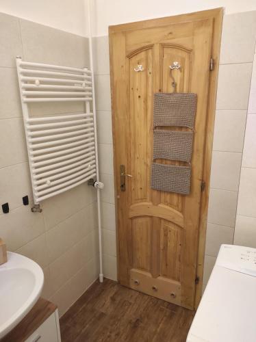 Łazienka z drewnianymi drzwiami i umywalką w obiekcie BudaWestHouse w mieście Budakeszi