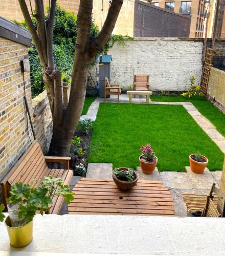 a small garden with a wooden bench and plants at 2 Bedroom Garden Flat /Kings Cross, Central London in London