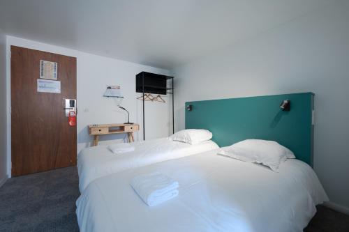 2 bedden in een hotelkamer met witte lakens bij Les Chevaliers des Balances in Saint-Aubin