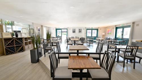 a restaurant with tables and chairs and windows at Les Chevaliers des Balances in Saint-Aubin